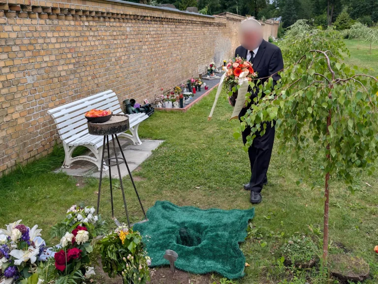 Persönlicher Abschied an einem Baumgrab auf einem Berliner Friedhof mit Blumen und Urnengrabstelle