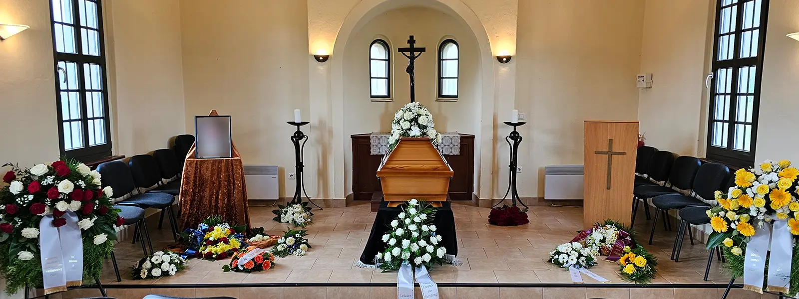 Persönlich gestaltete Erdbestattung mit Sarg und umfangreichem Blumenschmuck in einer Trauerhalle