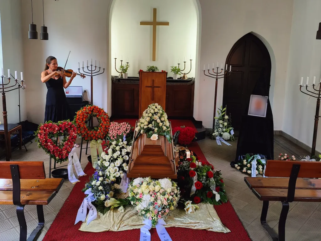 Persönlich gestaltete Erdbestattung in Berlin mit Sarg, Blumenschmuck und Live-Musik durch eine Geigerin
